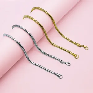 Sleek gold and silver stainless steel snake chain necklaces on a minimalist pink display