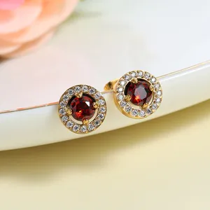 Detail of 18K gold-plated stud earrings with a red gemstone and white zircon halo
