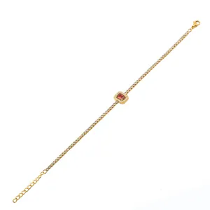 Detailopname van een gouden tennisarmband met een centrale rode rechthoekige edelsteen