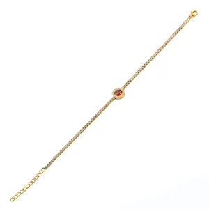 Detail van gouden armband met zirkonia en een rond rood edelsteen middenstuk