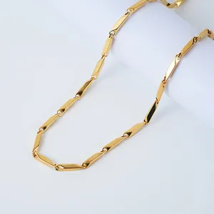 Detailed macro view of a polished golden stainless steel cuban link necklace on white background