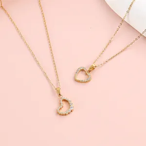 Macro detail of 18K gold-plated heart necklaces with micro-set zircon on pink background