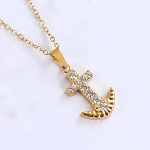 Macro detail of gold anchor cross pendant with sparkling white cubic zirconia stones