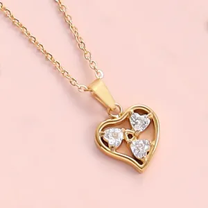 Detail of 18K gold heart pendant with triple cubic zirconia stones on a fine chain