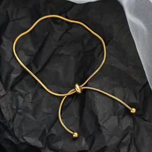 Close-up of 18K gold snake chain necklace with adjustable slider clasp and metal beads