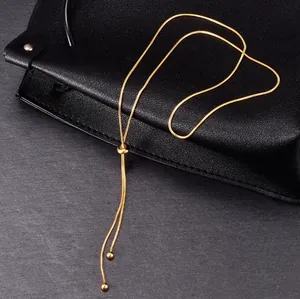 Detail of adjustable 18K gold snake chain necklace with sliding bead on textured background