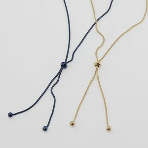 Macro view of adjustable snake bone chain necklaces in gold and navy blue finishes