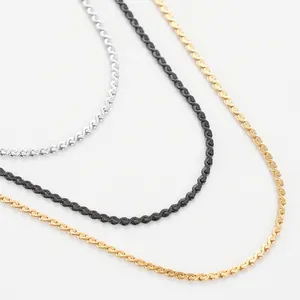 Macro shot of S-link chains in silver, gold, and black finishes on a white background