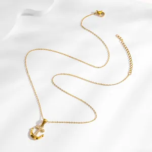 Gold plated anchor pendant necklace with micro-paved zircons on a white minimalist background