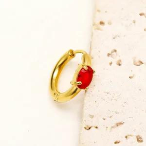 Dettaglio ravvicinato di un orecchino a cerchio placcato oro con zircone rosso