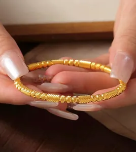 Detalle de brazalete de acero inoxidable dorado 18K con elegante diseño de cuentas