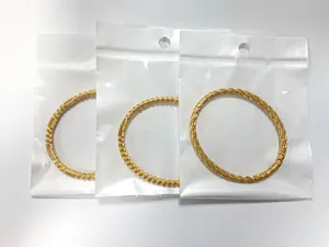 Detalle de tres brazaletes ovalados de acero inoxidable bañados en oro de 18K con texturas