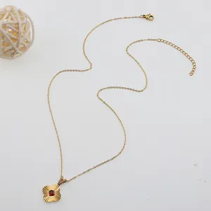 Gold titanium necklace with red gemstone flower pendant and lobster clasp on white background