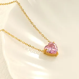 Macro-opname van de roze hartvormige zirkonia hanger aan een vergulde roestvrijstalen ketting