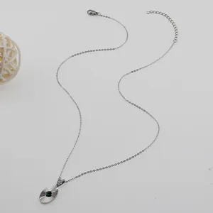 Macro view of silver necklace featuring an oval pendant with green gemstone