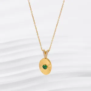 Detail of 18K gold necklace with emerald oval pendant featuring sunburst textures