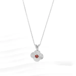 Detail of silver clover pendant with red gemstone and textured floral pattern petals