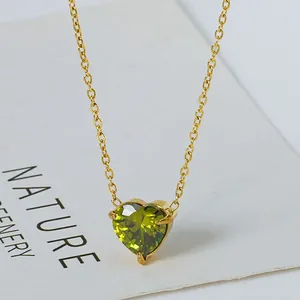 Macro-opname van een gouden ketting met olijfgroene zirkoon hartvormige hanger en klauwzetting