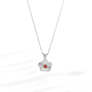 Macro view of silver flower pendant with red gemstone and textured floral petals
