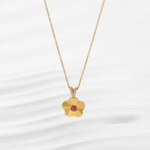 Macro shot of 18K gold flower pendant with red gemstone and sparkling stone bail