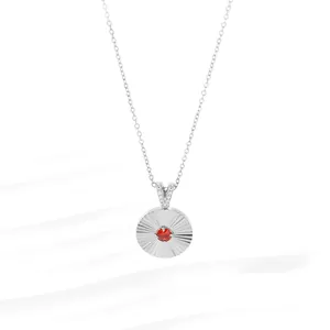 Macro detail of sunburst texture silver pendant with red stone and crystal accents