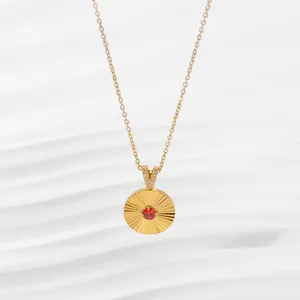 Detail of 18K gold-plated sunburst pendant necklace with a central red stone and zircon V-clasp