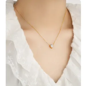 Detailopname van gouden hartjesketting met heldere zirkoon op de hals van het model