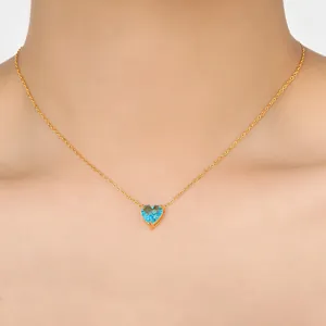 Detailopname van een hartvormige blauwe zirkoon hanger aan een goudkleurige roestvrijstalen ketting