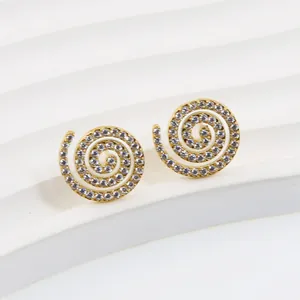 Macro view of gold spiral stud earrings with white zircon pavé setting on textured base