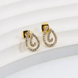 Close-up of golden teardrop stud earrings with pavé white zircons and spiral texture
