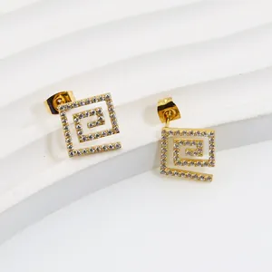 Macro view of gold hollow square earrings with cubic zirconia inlay and Greek key pattern