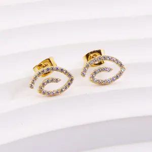 Close-up of golden spiral earrings with micro-pave cubic zirconia on white display