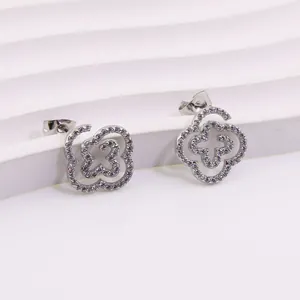 Detailed close-up of clover-shaped titanium steel earrings with pavé set white zircons