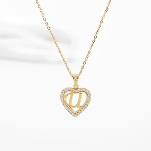 Detail of gold heart pendant necklace featuring micro-set stones and letter U