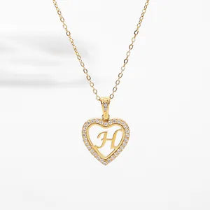 Close-up of heart-shaped letter H pendant with pavé set crystals on a gold chain