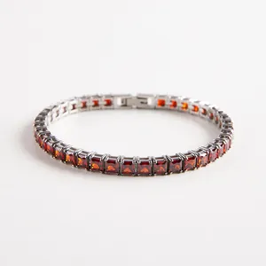 Macro shot of silver tennis bracelet with square-cut red zircon stones and secure metal setting