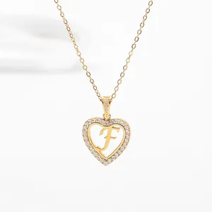 Detail of gold heart pendant with letter F and pavé crystals on a delicate chain