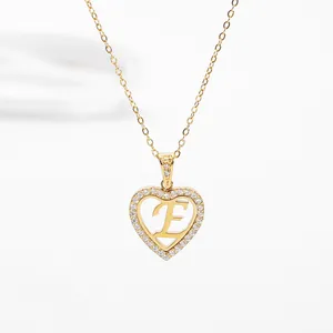 Detailed view of heart pendant with paved zircon stones and gold letter E on a link chain