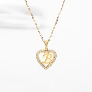 Detail of gold heart pendant necklace with hollow design and letter B crystal inlay