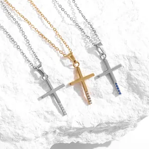 Tres collares de cruz con circonitas en oro y plata con cadenas finas sobre fondo de piedra blanca