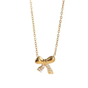 Elegante goldene Schleifenkette mit weißen Zirkonia-Anhängern an einer Kreuzkette