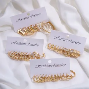 Set de pendientes de aro dorados con diseño trenzado y perlas sobre seda blanca