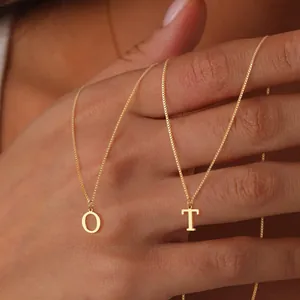 Minimalist gold box chain necklace featuring letter O and T pendants on neck