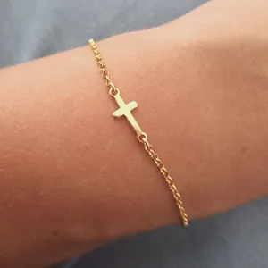 Elegante pulsera de cadena fina dorada con colgante de cruz minimalista en la muñeca