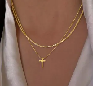 Double-layered gold necklace with shimmering chains and a cross pendant on model