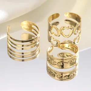 Three-piece set of gold hollow heart and layered open rings on a reflective mirror base