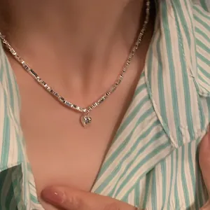 Minimalist silver-tone heart pendant necklace with square link chain on a model