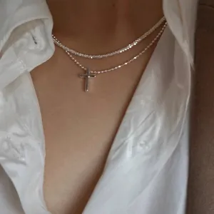 Silver layered necklace set with a polished cross pendant and thin shimmering chain