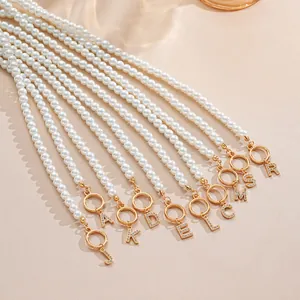 Detailed macro of pearl necklaces featuring gold OT clasps and diamond-set initial pendants
