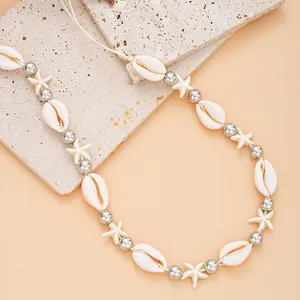 Détail du collier de perles en coquillage avec étoiles de mer sur pierre texturée
